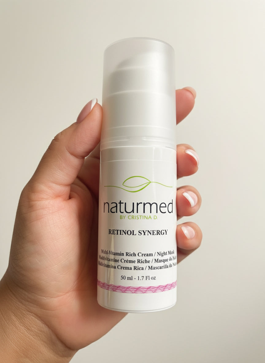 Hand holding a bottle of naturmed Retinol Synergy cream against a neutral background
