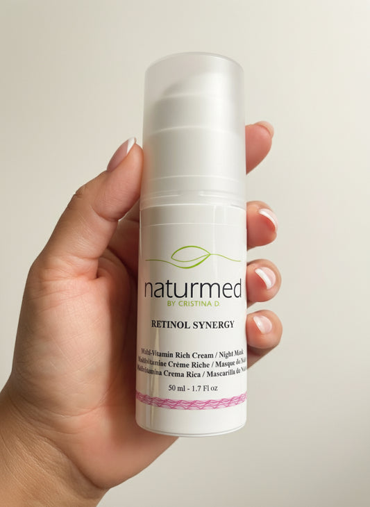 Hand holding a bottle of naturmed Retinol Synergy cream against a neutral background